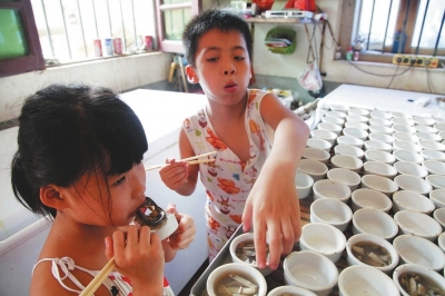 在“吓溜”家，两个小孩在吃土笋冻。男孩一口一个，吃得开心；女孩则怕“虫”，吃得小心翼翼。